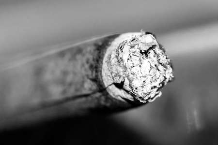 Smoldering brown cigarette, ashes, macro shot with blurred backgroundの写真素材