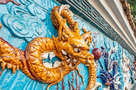 Ceramic wall decor in the form of a yellow Chinese dragon headの写真素材