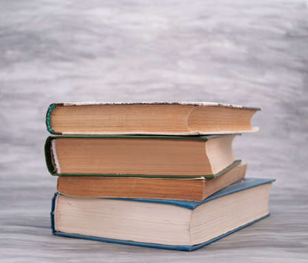 Old books lie in a pile on a gray background