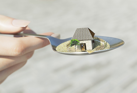 woman hand holding spoon with paper house real estate business concept photoの写真素材