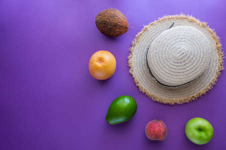 Tropical summer vacation concept with hat, coconut, avocado, peach and orangeの写真素材