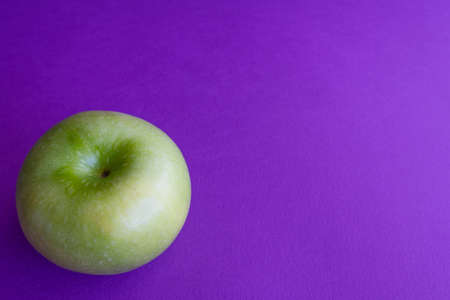 Green apples on purple background. Color trends concept with copy spaceの写真素材