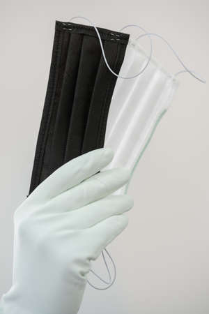 Man holds rubber gloves black and white face masks.