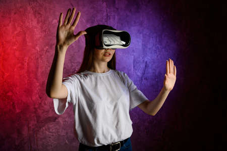 Young woman touching the air during the VR experience. Blue and red backgroundの写真素材