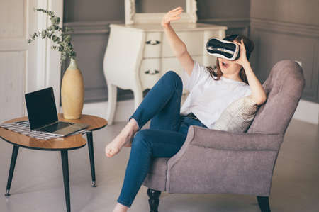 Young woman adjusting her VR headset and smiling while at homeの写真素材
