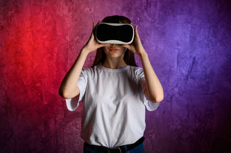 Young woman touching the air during the VR experience. Blue and red backgroundの写真素材