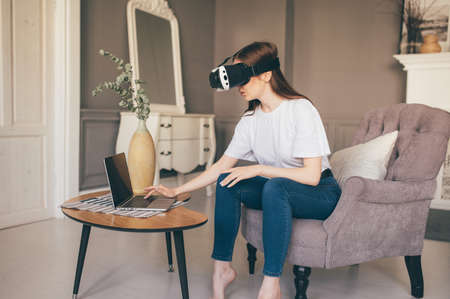 Young female programmer testing a new app with virtual reality glasses in homeの写真素材