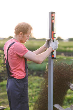 man measures the level. Male specialist in outdoor checking the post with level
