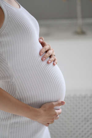 pregnant woman in white sweater holding her belly.  close up of happy pregnant
