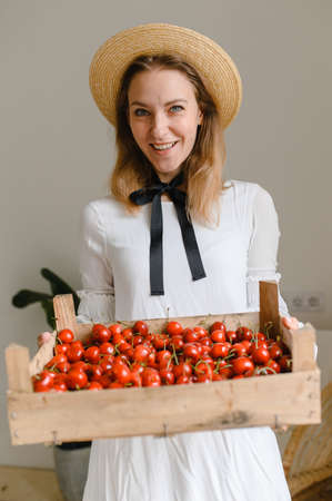 happy woman with cherries wearing hat and white dress. Healthy eating, dieting, vegetarian food and people conceptの写真素材