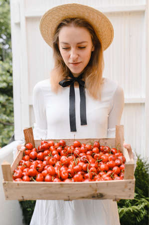 happy woman with cherries wearing hat and white dress. Healthy eating, dieting, vegetarian food and people conceptの写真素材