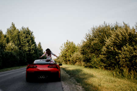 Traveling by car - happy couple in love go by cabriolet car in sunset time