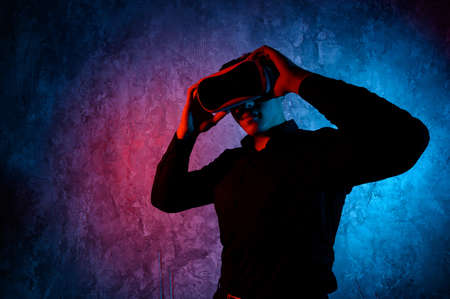 Closeup of young man wearing virtual reality goggles in modern studio. Smartphone using with VR headset.の写真素材