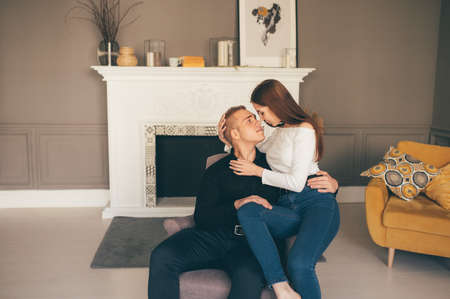 The happy man and woman sit on the background of the white fireplaceの写真素材