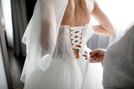 Bride being prepared for wedding. lacing bridesmaid dresses
