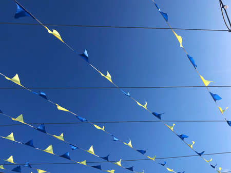 A row of decorations small flags fluttering in the wind against the background of a deep blue sky