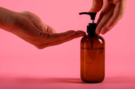 Man hands pushing pump plastic bottle isolated on pink background, clipping path. Mock upの写真素材