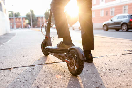 Legs of a man in stylish outfit stand on electric scooter on the streetの写真素材