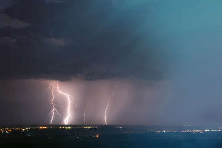 lightning storm over city. Lightning strike over dark blue sky in night city.