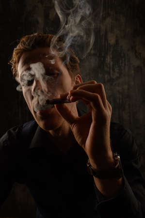 Brutal Mystery man with cigar and smoke isolated on black backgroundの写真素材