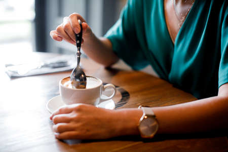 Closeup of hand with coffee cup in a cafeの写真素材