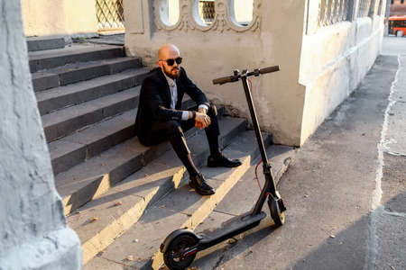business and people and concept - young businessman riding electric scooter outdoors