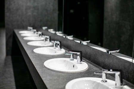 Faucets with washbasin in public restroom in gray colorsの写真素材