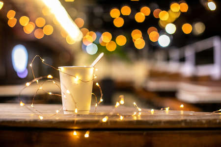 paper a cup of delicious coffee, against the background of New Years garlands
