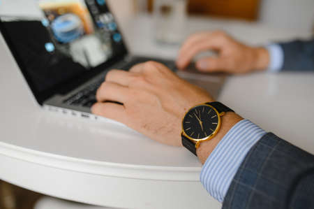 a man in a black watch is working at a laptopの写真素材