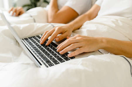 young couple using laptop together in bed. 