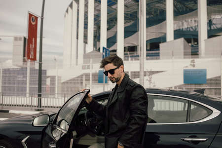 young fashionable man in glasses near the car