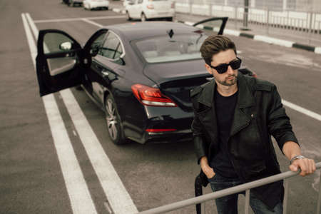 young fashionable man in glasses near the car