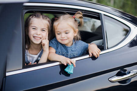 Two Baby girl looking through car window. happy children.の写真素材