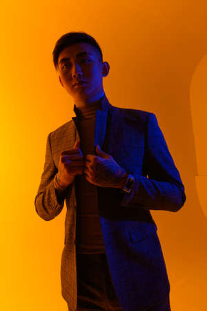 Portrait of a young asian man standing over yellow background. Fashion asian man