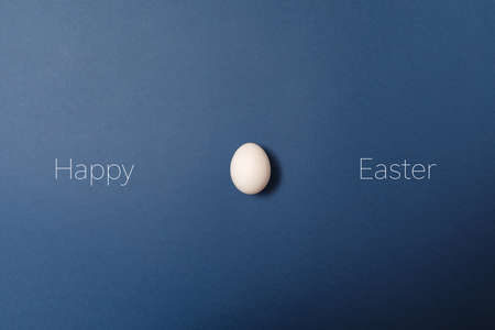 White easter egg with happy easter word, holiday concept. Blue background. Top viewの写真素材
