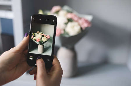 blogger takes a photo of a bouquet of flowersの写真素材