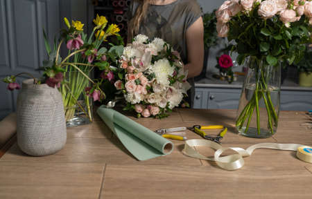 Handsome fresh bouquet. Flowers delivery. Woman florist create flower arrangement in a wicker...