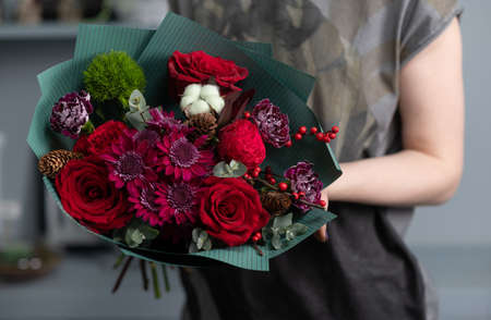 Close-up flowers in hand. Florist workplace. Woman arranging a bouquet with roses, chrysanthemum, carnation and other flowers. A teacher of floristry in master classes or coursesの写真素材
