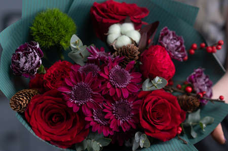 Close-up flowers in hand. Florist workplace. Woman arranging a bouquet with roses, chrysanthemum,...