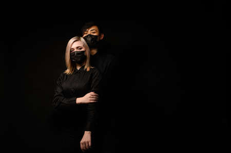 An Asian man hugs a European girl. They are wearing medical masks. Virus, bad ecology. Coronavirus conceptの写真素材