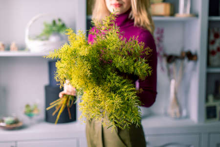  young florist girl with a big bouquet of mimosa in hands.の写真素材
