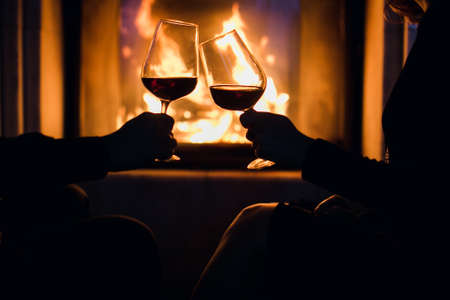 Young couple have romantic dinner with wine over fireplace background. 