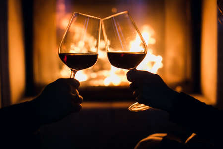Young couple have romantic dinner with wine over fireplace background. の写真素材
