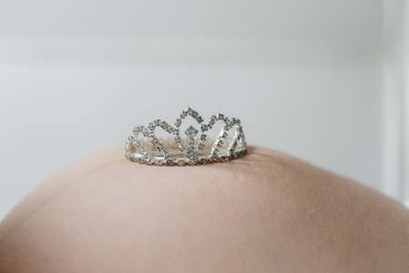Pregnancy baby belly newborn expectation. toy crown on the bellyの写真素材