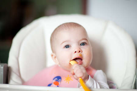 Portrait Of Happy Young Baby girl In High Chair. Baby eatingの写真素材