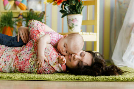 Beautiful young woman and her charming little daughter are hugging and smiling