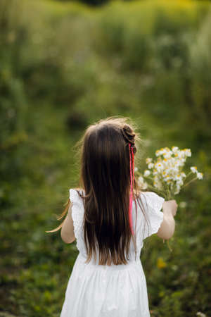 portrait little cute girl with flowers. Girl in the garden with a bouquet of chamomile