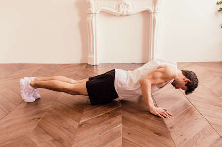 Muscular Athletic Fit Man is Doing Push Up Exercises at Home in His Bright Apartment with...