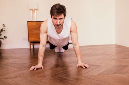 Muscular Athletic Fit Man is Doing Push Up Exercises at Home in His Bright Apartment with...