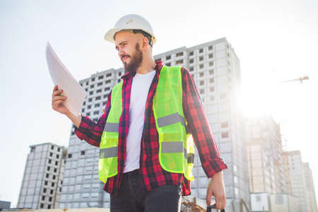 civil engineer in a white helmet on the background of houses under construction.